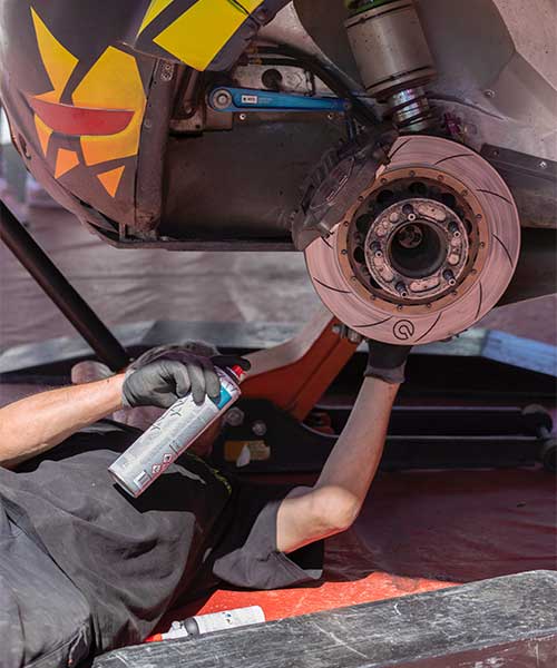 man spraying brake cleaner on brakes